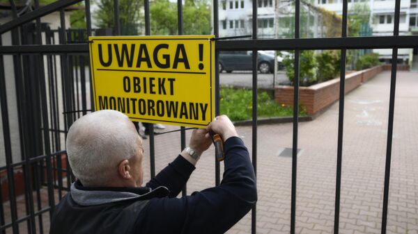 Представитель мэрии вешает предупреждающий знак на ворота школы при российском посольстве в Варшаве