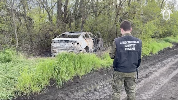 Сотрудник СК на месте обнаружения обгоревшего автомобиля молодых людей, пропавших четыре дня назад в Краснодарском крае. Кадр видео