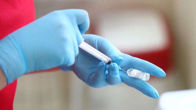 Медицинский работник набирает в шприц компонент вакцины 
