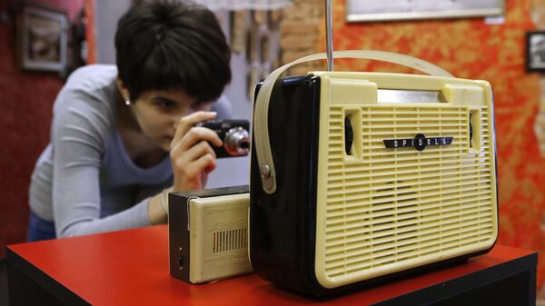 Посетительница фотографирует радиоприемник Spidola на выставке Чемодан воспоминаний в Санкт-Петербурге