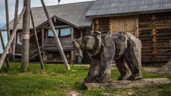 Деревянная фигура медведя на детской площадке в деревне Кинерма в Карелии