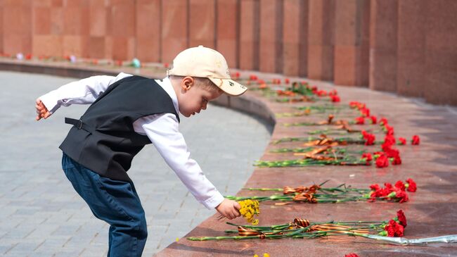 Мальчик возлагает цветы к мемориалу у Вечного огня в Астане