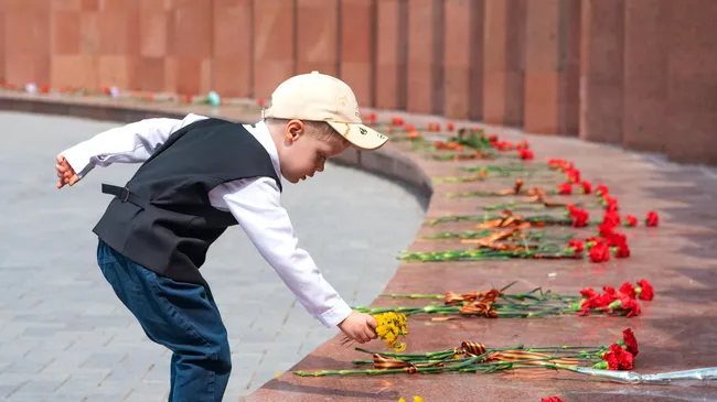 Мальчик возлагает цветы к мемориалу у Вечного огня в Астане