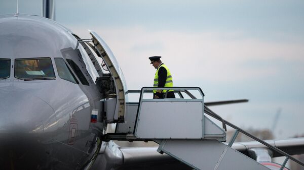Пилот поднимается по трапу на борт самолета