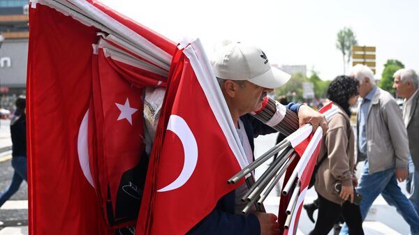 Мужчина несет государственные флаги Турции на улице в Анкаре