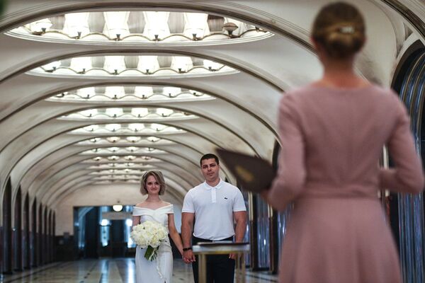 Пара молодоженов во время торжественной церемонии бракосочетания на станции Маяковская Московского метрополитена