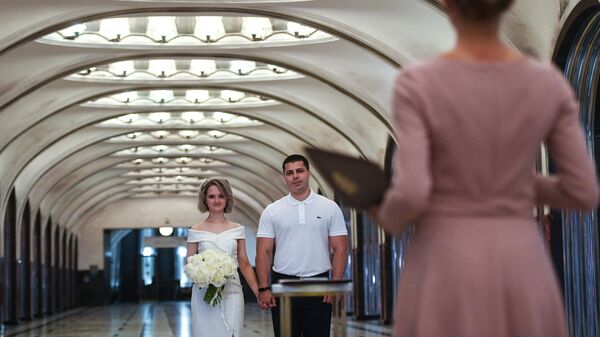 Пара молодоженов во время торжественной церемонии бракосочетания на станции Маяковская Московского метрополитена