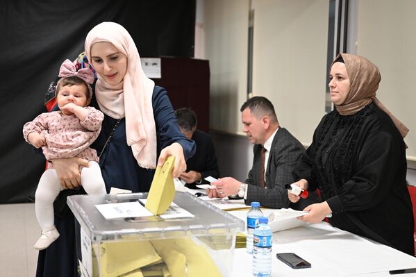 Женщина с ребенком на избирательном участке во время голосования на всеобщих выборах в Стамбуле