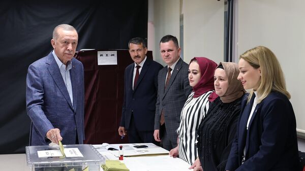 Президент Турции Реджеп Тайип Эрдоган и члены избирательной комиссии во время голосования на избирательном участке в ходе всеобщих выборов в Стамбуле