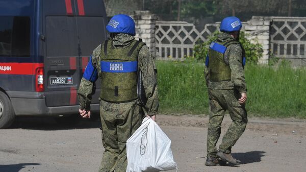 Сотрудники СЦКК на улице Луганска, подвергшегося обстрелу со стороны ВСУ