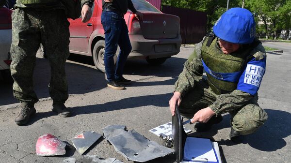 Сотрудник СЦКК возле фрагментов ракеты на улице Луганска