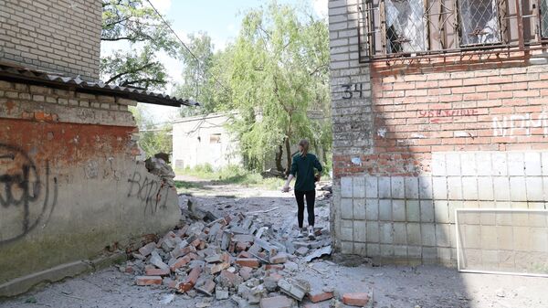 Девушка во дворе жилого дома, пострадавшего в результате обстрела ВСУ города Ясиноватая