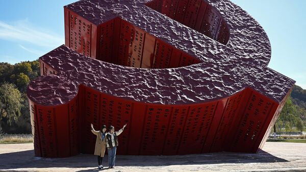 Люди фотографируются рядом с памятником коммунистам в Нанниване, провинция Шэньси на северо-западе Китая