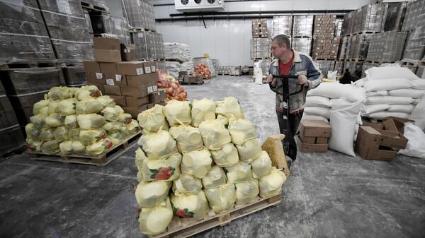 Волонтер перемещает телегу с продуктовыми наборами на складе в Бердянске