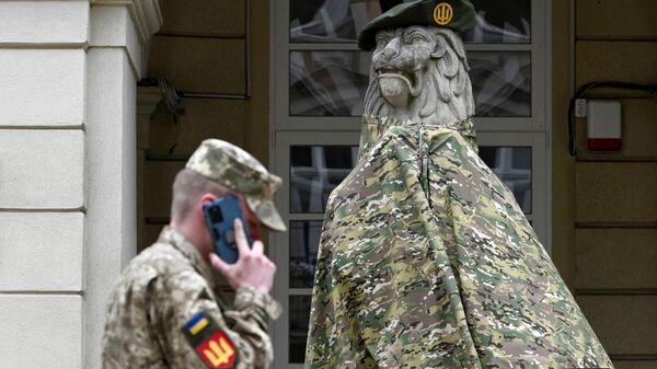 Военнослужащий около статуи льва, наряженной в военную форму, возле Львовской мэрии