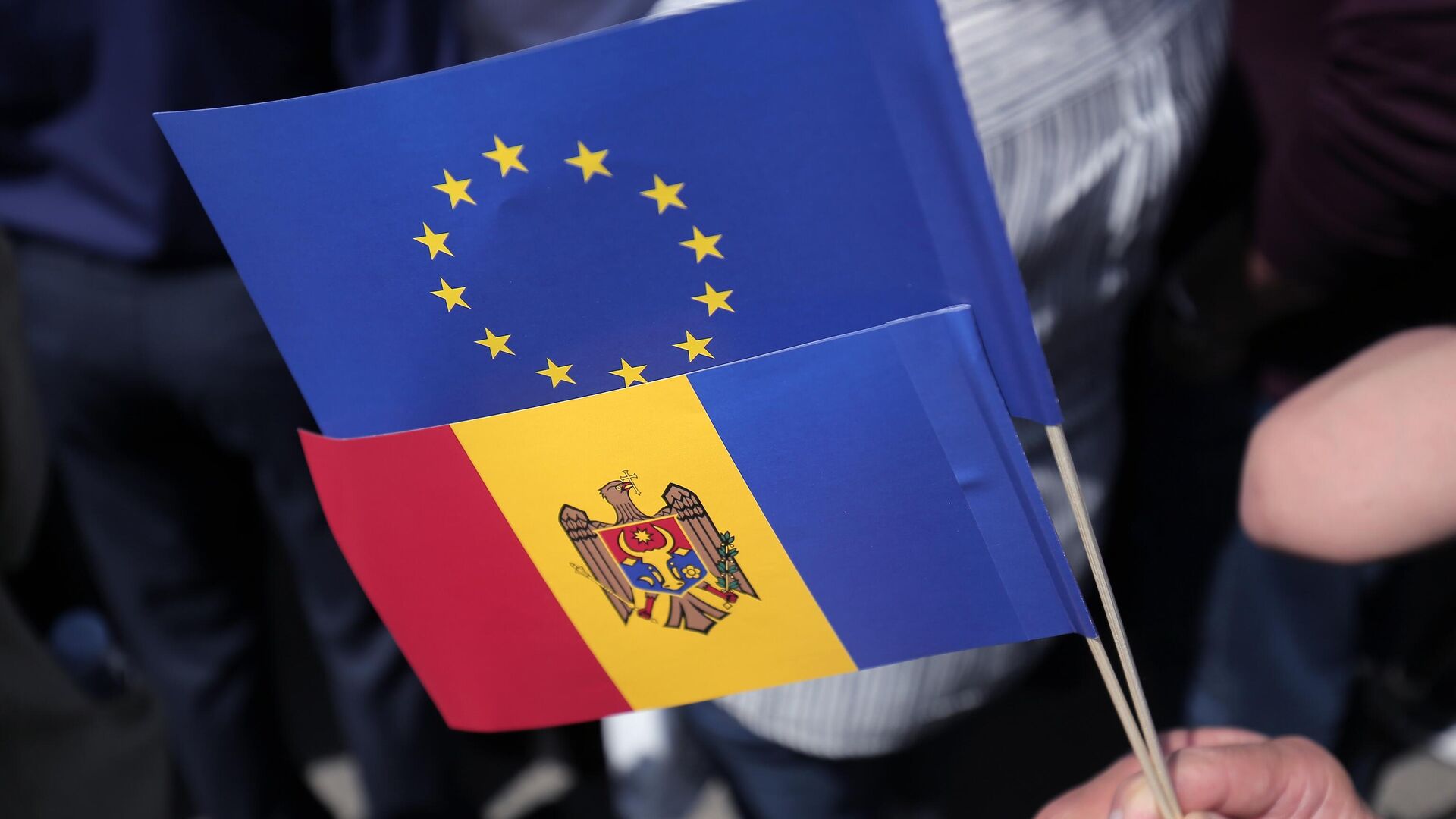 Флаги Молдавии и Евросоюза в руках одного из участников митинга на площади Великого Национального Собрания в Кишиневе - РИА Новости, 1920, 21.05.2023