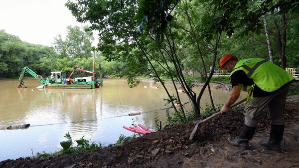 Сотрудник ГК Акватория расчищает берег пруда на территории музея-усадьбы Кусково в Москве