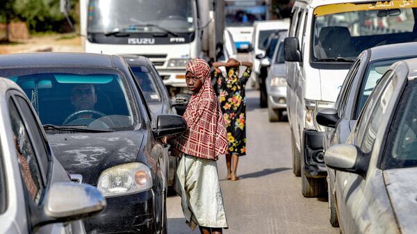 Девочки-мигрантки из стран Африки к югу от Сахары просят милостыню во время автомобильной пробки на дороге в Алжире
