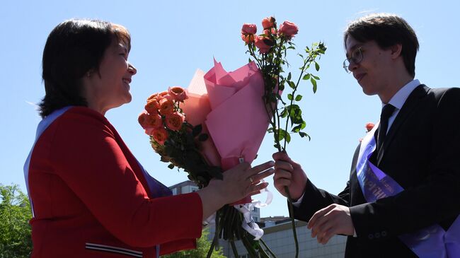 Выпускник вручает цветы классному руководителю на празднике Последний звонок в гимназии №2 во Владивостоке