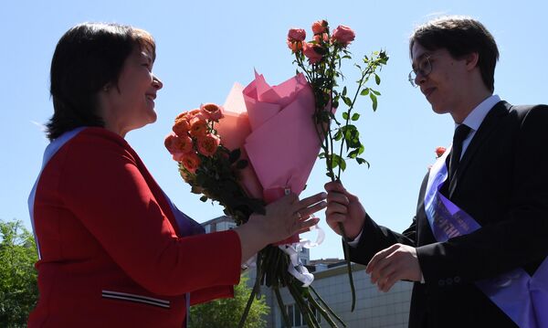 Выпускник вручает цветы классному руководителю на празднике Последний звонок в гимназии №2 во Владивостоке