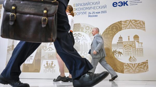 Участники проходят рядом со стендом с символикой Евразийского экономического форума в Москве