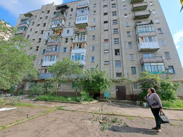 Женщина во дворе многоквартирного дома, поврежденного в результате обстрела со стороны ВСУ города Ясиноватая