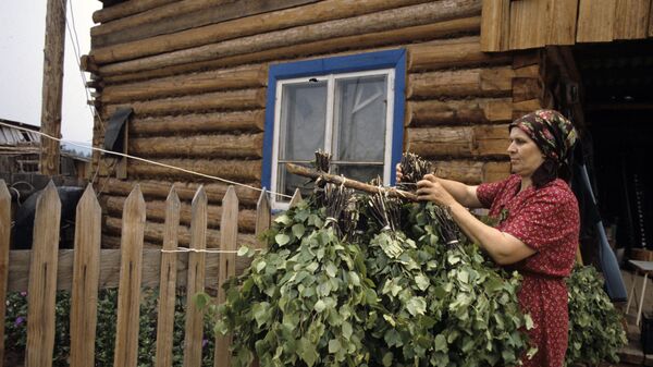 Жительница деревни вывешивает сушить березовые веники