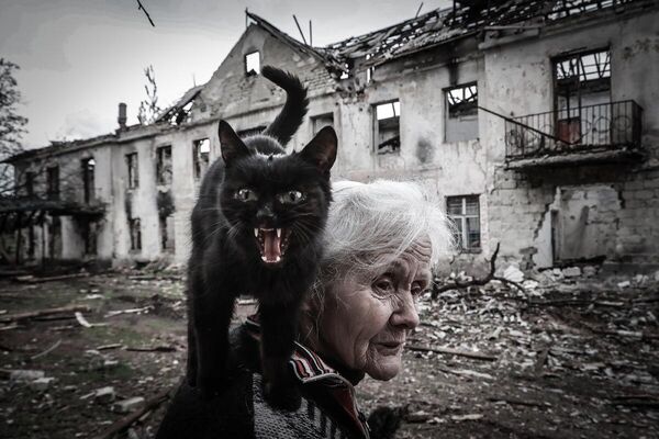 Жительница разрушенного поселка Светличное баба Нина с бездомным котом. ЛНР, 2022
