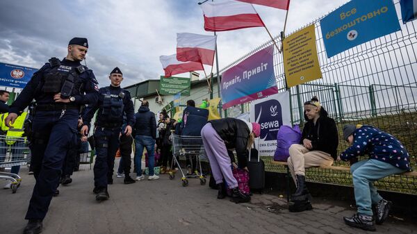 Польские полицейские проходят мимо украинских беженцев на контрольно-пропускном пункте Медыка — Шегини на польско-украинской границе