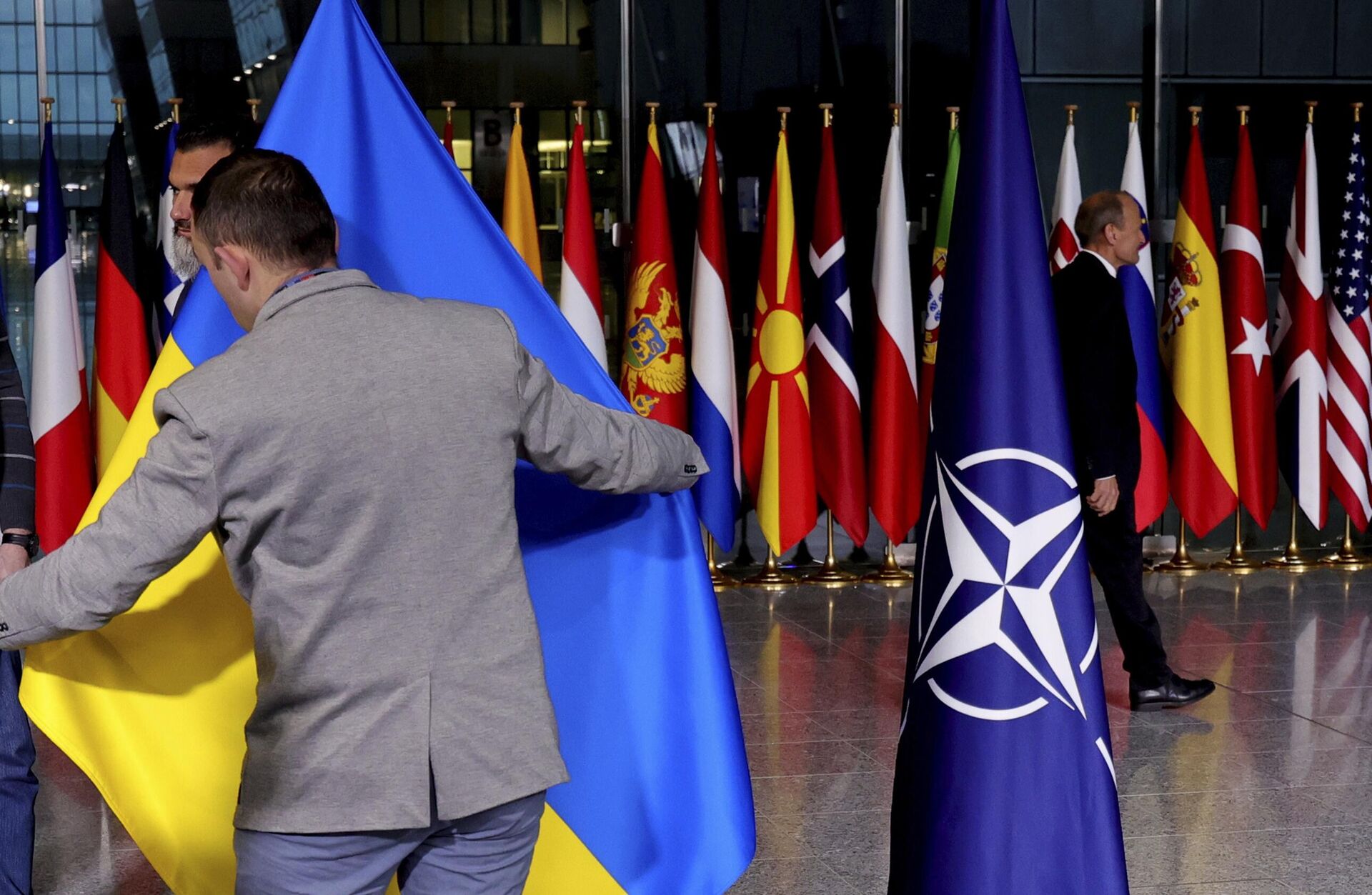 Сотрудник службы протокола поправляет украинский флаг в штаб-квартире НАТО в Брюсселе - РИА Новости, 1920, 10.07.2023