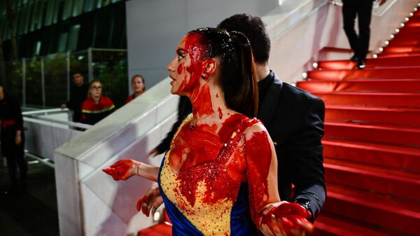 Охрана уводит женщину в платье под цвет украинского флага с красной дорожки Каннского кинофестиваля, 2023 год