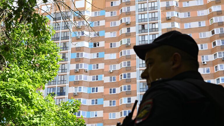 Сотрудник полиции у жилого дома, пострадавшего в результате атаки беспилотника, на улице Профсоюзная в Москве