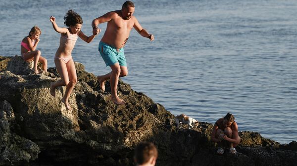 Отдыхающие прыгают в воду на пляже поселка Оленевка в Крыму