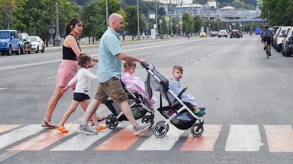 Прохожие с детьми переходят дорогу по пешеходному переходу