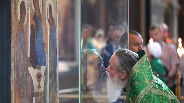 Священнослужитель у иконы Святой Троицы перед началом патриаршего служения по случаю принесения иконы в храм Христа Спасителя в Москве