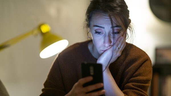 Расстроенная женщина смотрит в смартфон