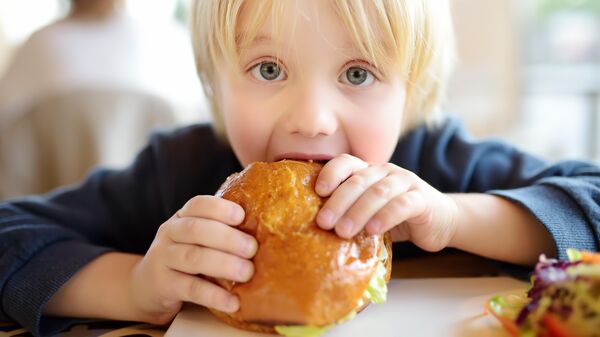 Мальчик ест гамбургер
