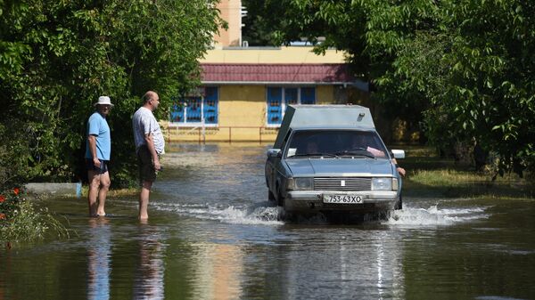 Автомобиль проезжает по одной из подтопленных улиц в Новой Каховке после разрушения Каховской ГЭС