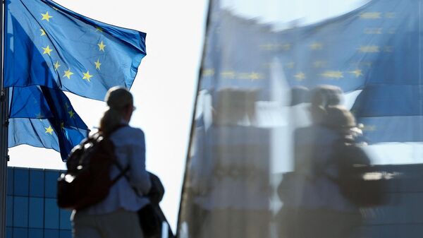 Женщина проходит мимо флагов Европейского союза в Брюсселе