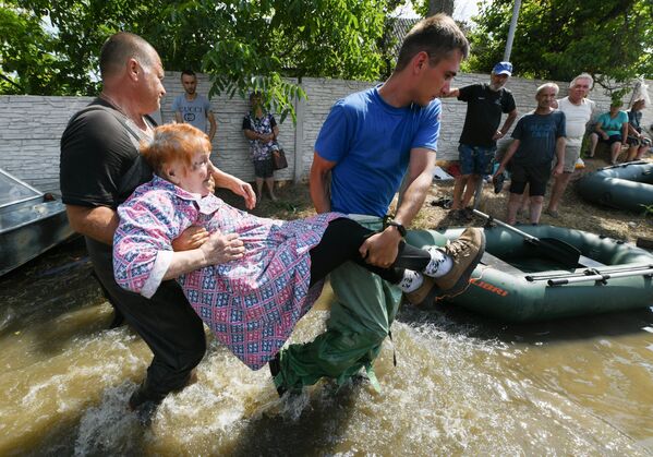 Волонтеры и спасатели МЧС проводят эвакуацию людей в городе Голая Пристань после подтопления