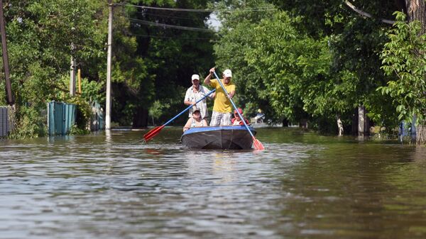 Местные жители плывут на лодке в ходе эвакуации волонтерами и спасателями МЧС в городе Голая Пристань после подтопления