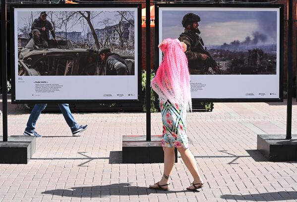 Девушка смотрит фотографии, представленные на выставке победителей Всероссийского конкурса военной фотожурналистики на Арбате в Москве