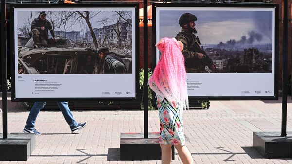 Девушка смотрит фотографии, представленные на выставке победителей Всероссийского конкурса военной фотожурналистики на Арбате в Москве