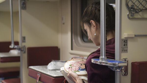 Девушка вышивает крестиком, пока едет в поезде Таврия, следующем по маршруту Санкт-Петербург - Севастополь
