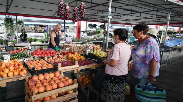 Покупатели и продавец на овощном рынке в Симферополе