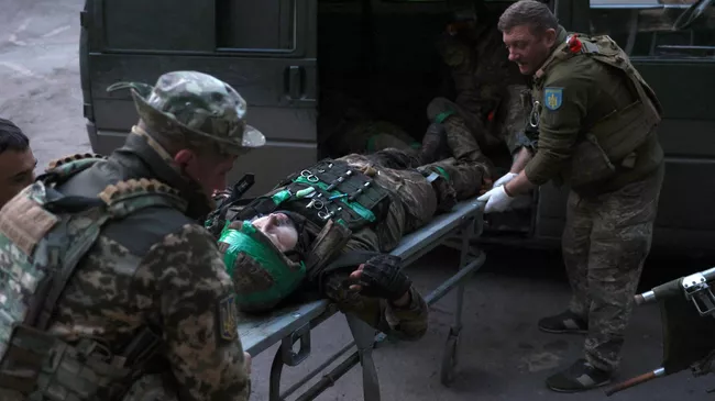 Украинские военные медики несут раненого военнослужащего, доставленного с передовой