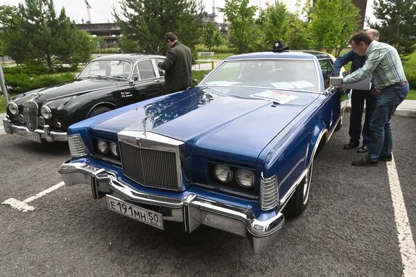 Владельцы клеят наклейки участников на машины Jaguar Mk1 и Lincoln Continental Mark IV (справа) перед стартом ралли на классических автомобилях Из прошлого в будущее в Москве