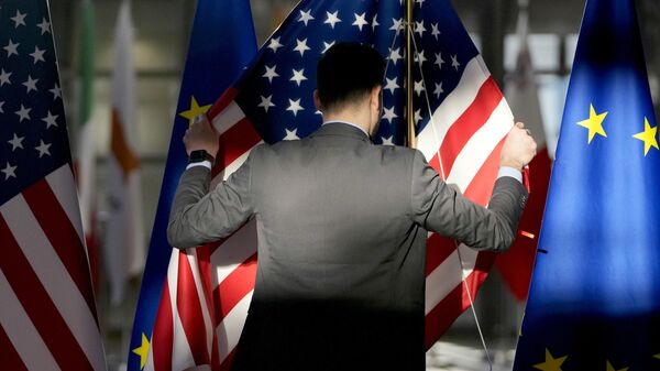 Сотрудник поправляет флаги США и ЕС в здании Европейского совета в Брюсселе