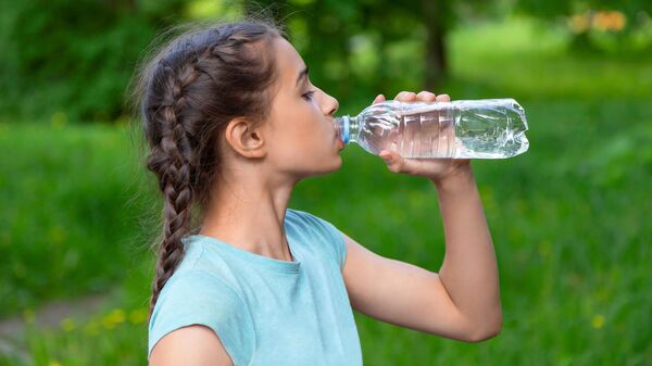 Девочка пьет воду из бутылки