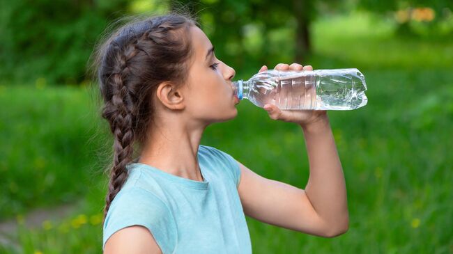 Девочка пьет воду из бутылки